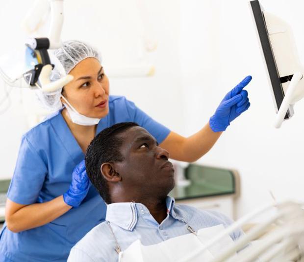 Patient and dental team member looking at computer monitor