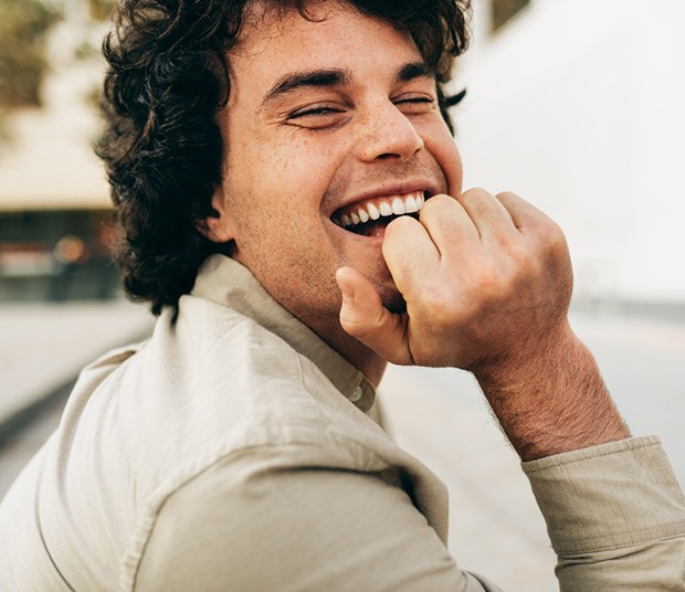 Man outside walking across road and smiling