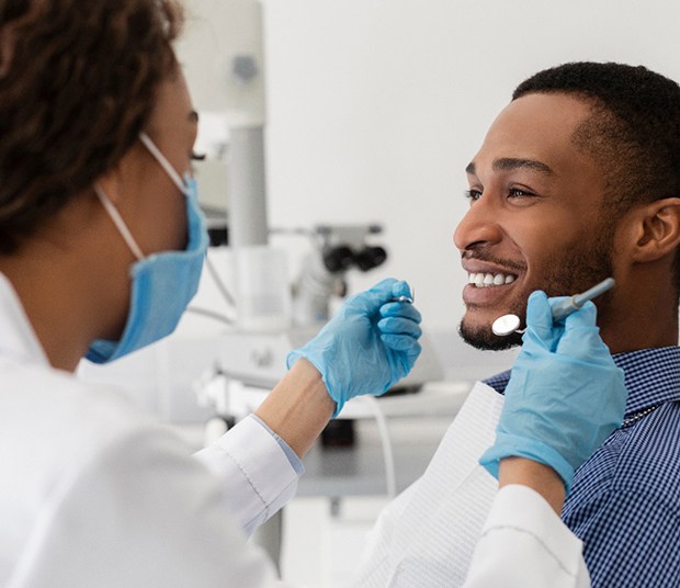 A dentist about to check a smiling young man’s teeth