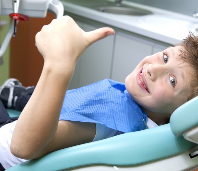 Young dental patient giving thumbs up during first children's dentistry visit