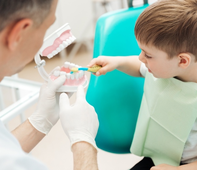 Dentist showing child how to brush teeth and discussing non-nutritive habits