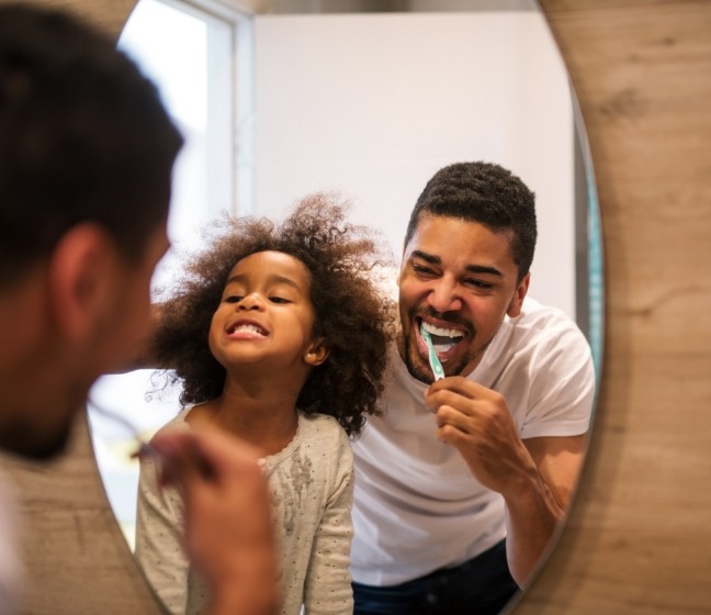 Father and child brushing teeth together to prevent dental emergencies