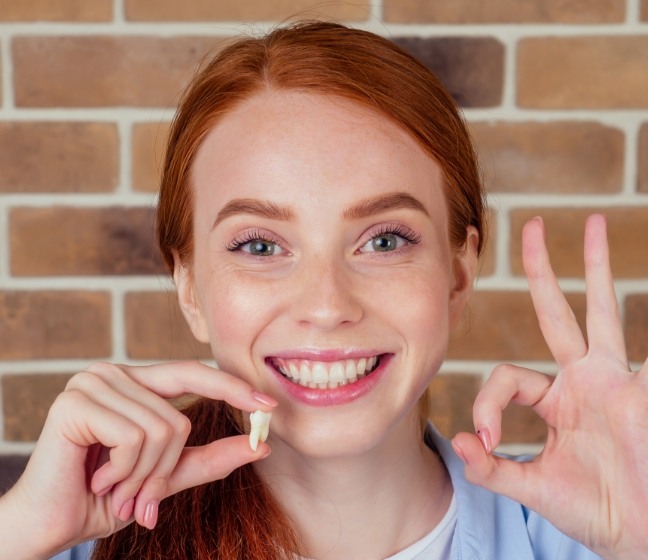 Woman holding tooth after extraction