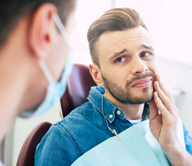 An unhappy man seeing his dentist for gum disease treatment