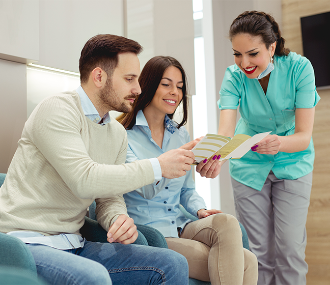 Dental patients and team member reviewing dental insurance forms