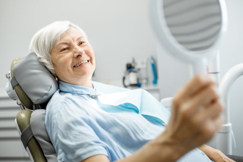 a patient looking at her dentures in a mirror