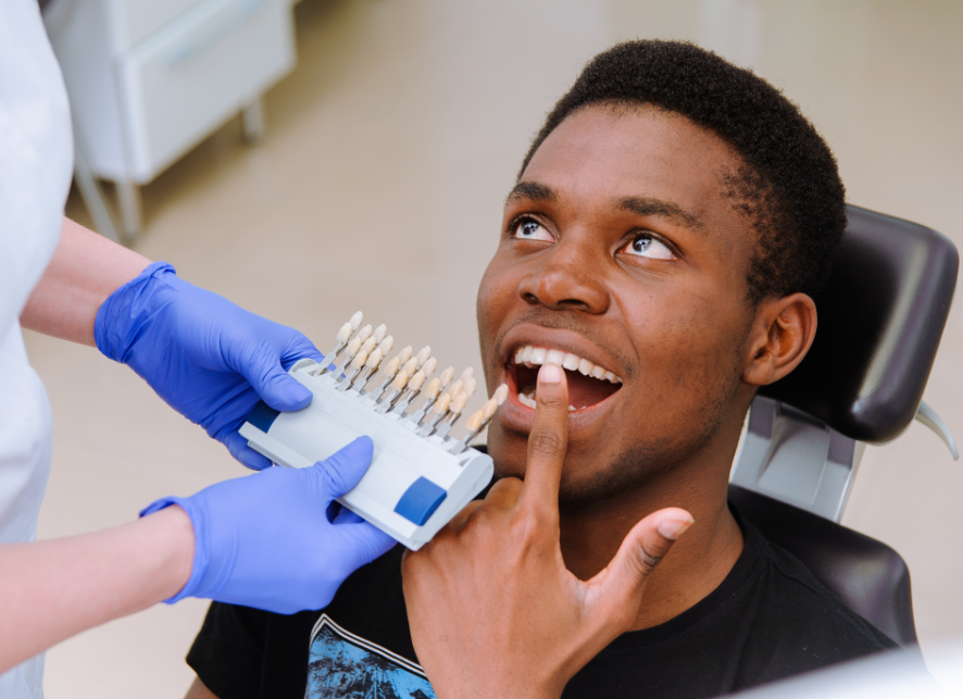 Man pointing at teeth while dentist holds veneer tray